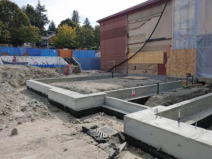 a building with the siding removed and low concrete rectangle walls