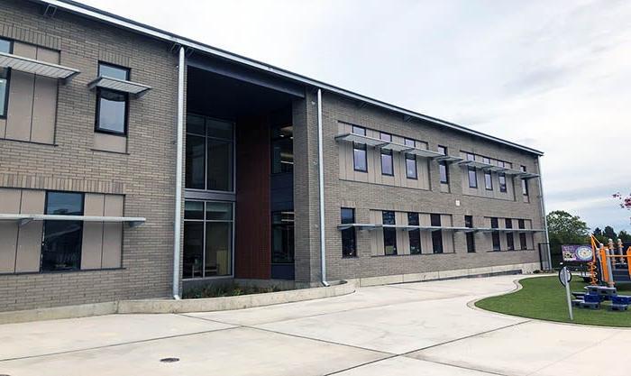 a two story gray brick building with windows