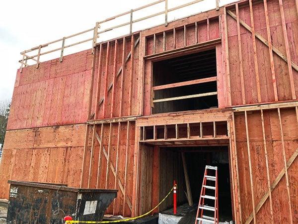 a partially constructed 2 story building addition attached to a brick wall