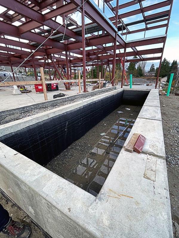 a concrete frame lined with black with a steel framework in the background