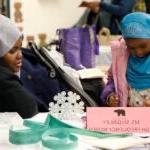 A parent watches a student as she works on a project in a classroom