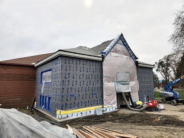 a partially buillt 2 story building with plastic over the entry