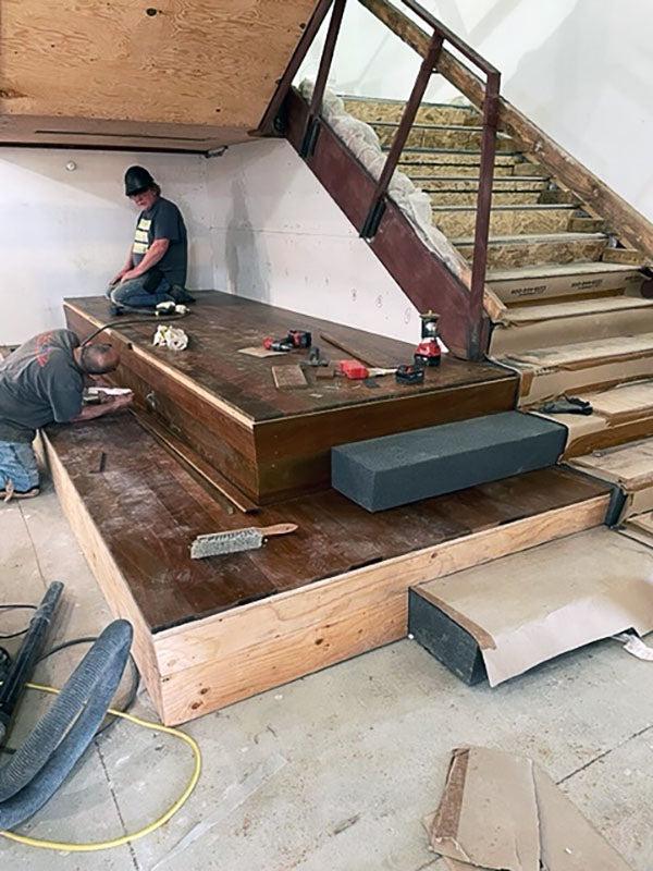 two people working on large platforms by some stairs