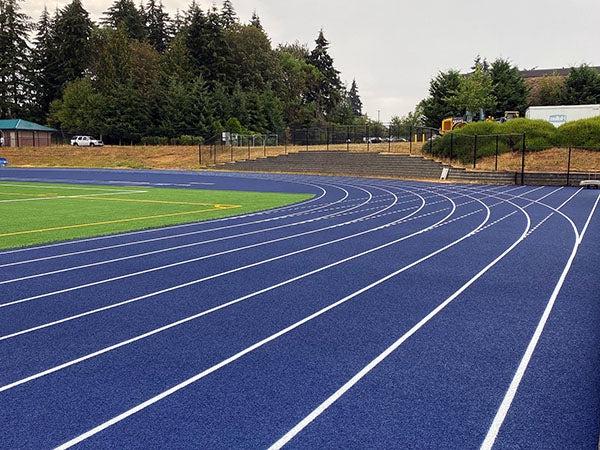 a blue running track with a green field next to it