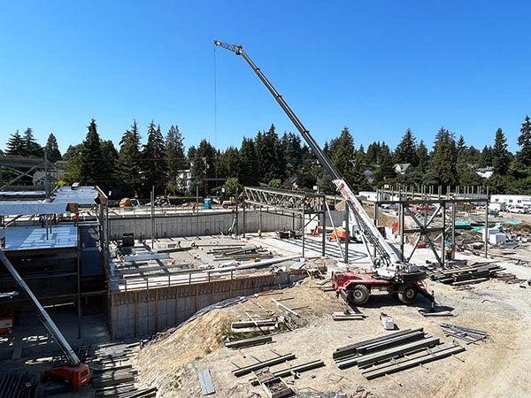 a crane is lifting steel beams over a concrete slab