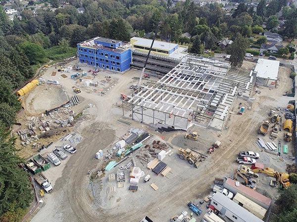 aerial view of a large construction site with part of the building showing walls and part still structural steel