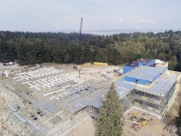 Aerial view of a large construction site surrounded by evergreen trees