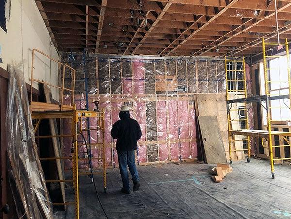 a wood framed wall and ceiling has pink insulation behind clear plastic