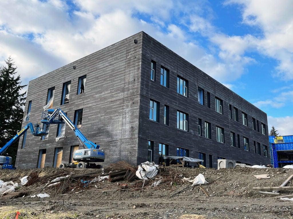 3-story gray brick covered building with a lift by one window