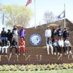 A group of students sits together near the Hampton University sign