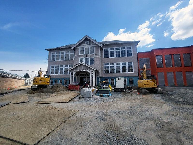 A three story building with a peaked roof over the entry has windows on all levels