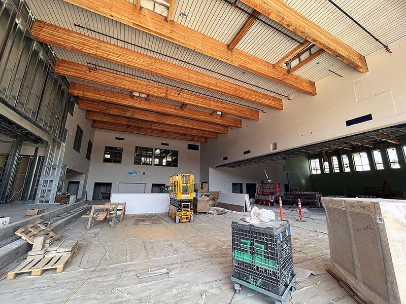 a two story room with wood beams on the ceiling and a raised concrete stage and steps to the right