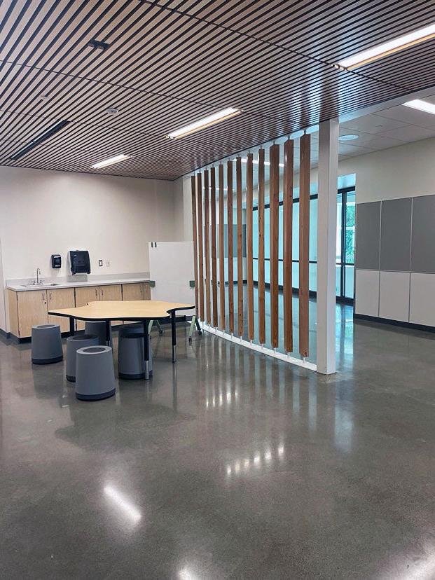 indoor space with a slated ceiling, a table, stools, and a counter and sink. it is separated from the hall by a partial wall