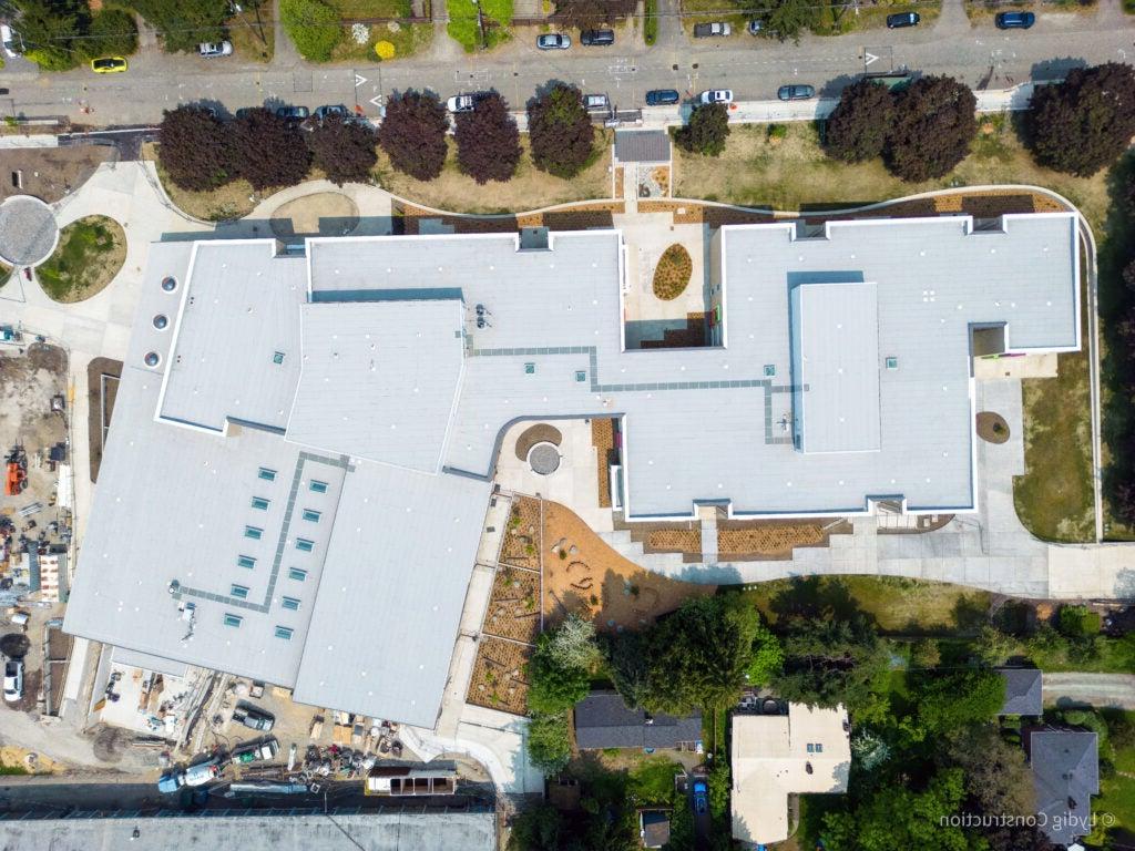 aerial photo of a large building with a road at the top and trees along the road