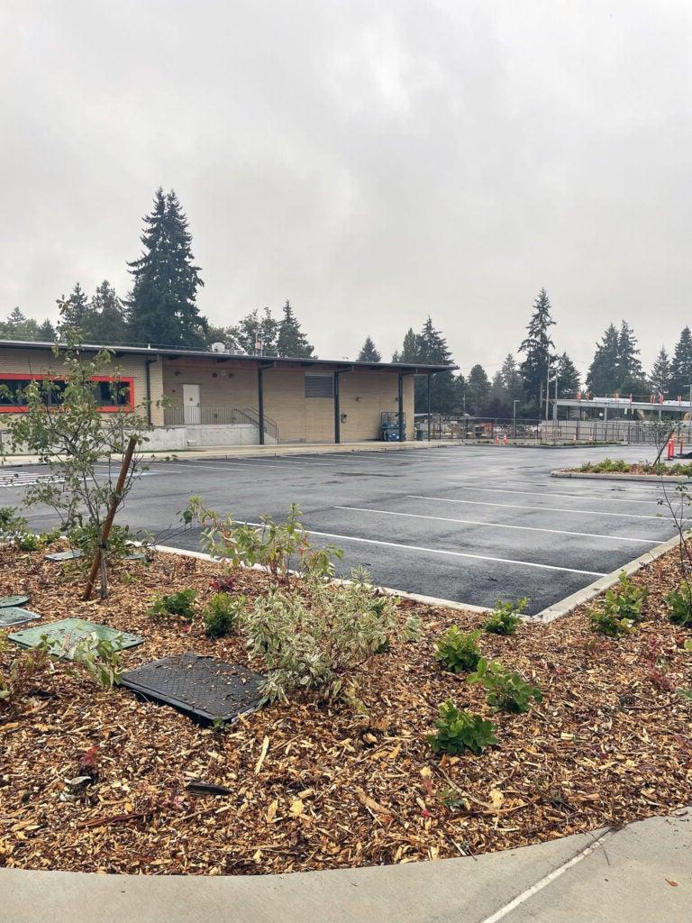 a parking lot next to a one story building with an orange window frame