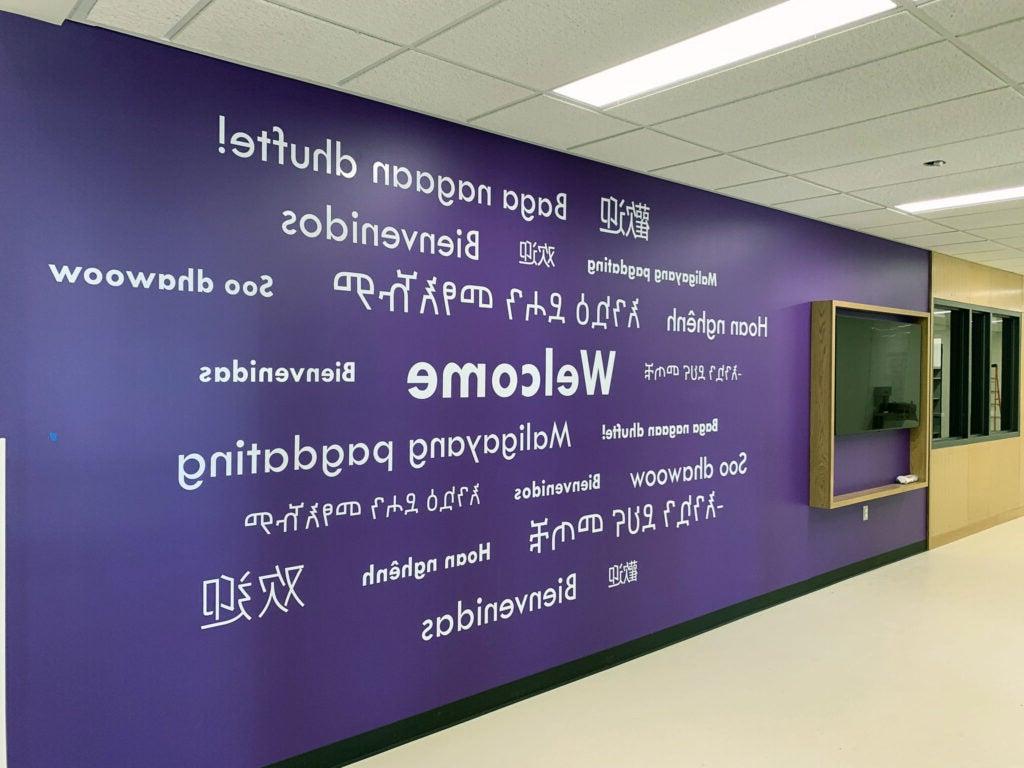 a purple wall has the word Welcome in multiple languages