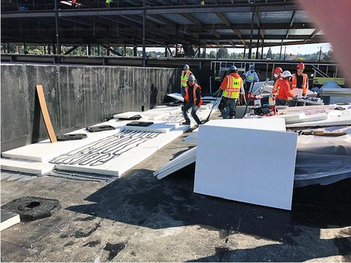 A group of men in orange vests and helmets working on a construction site