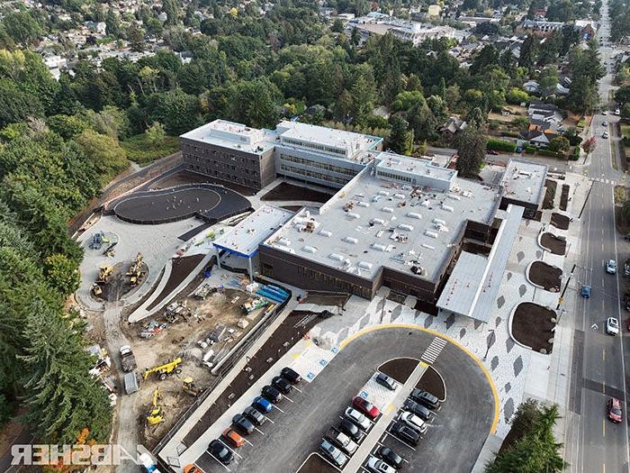 aerial view of a large building with a parking lot and trees