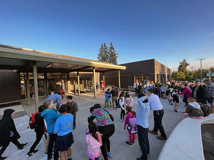 a group of adults and children outside of a building