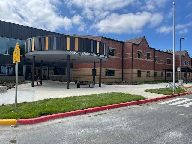 a two story brick building has a circular entry canopy with colored panels