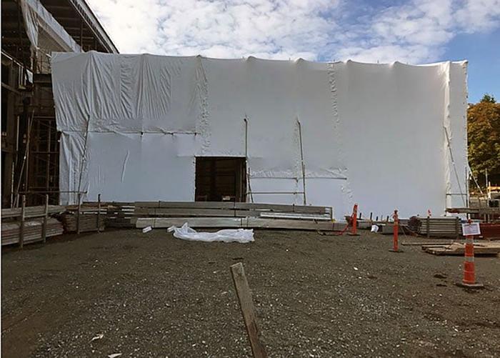 A building is wrapped in white material with a hole for a door.