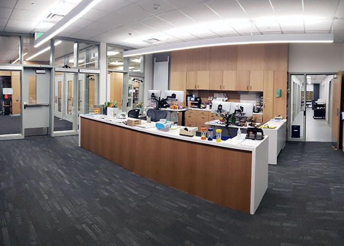 an office with a reception desk and full height glass windows