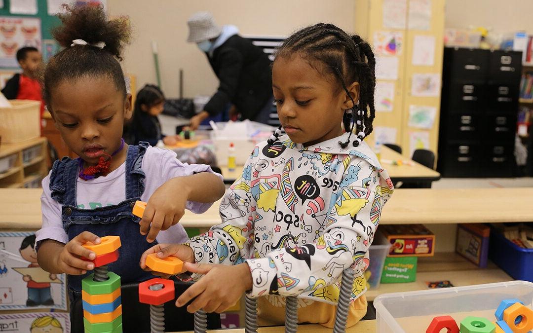 Two students in a classroom build blocks together