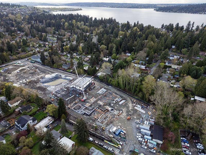 aerial of a large construction project with a crane, equipment, and mud. there is a lake in the distance