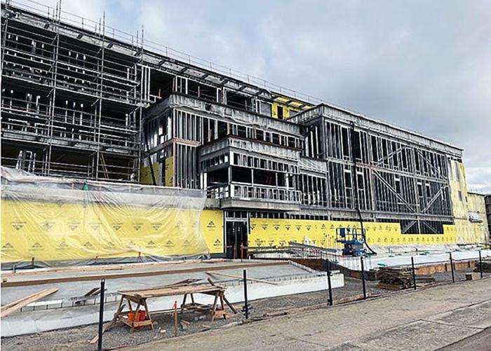 a 4-story building under construction has metal framing and the bottom floor has yellow sheathing