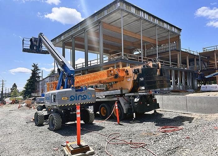 exterior of a partially built wing of a building withe a roof and construction equipment