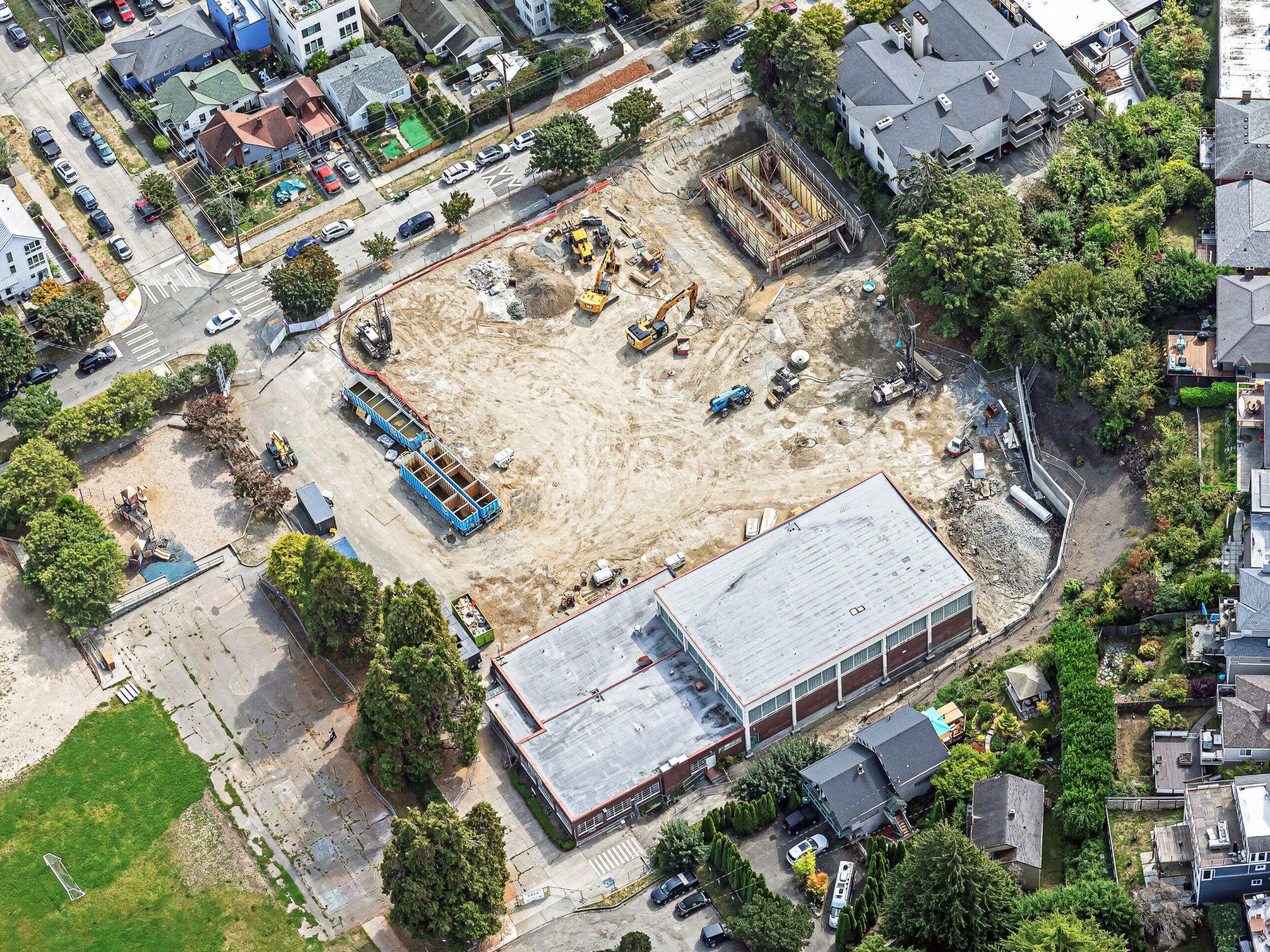 aerial of a construction site that is about a full block. there is a building on one side