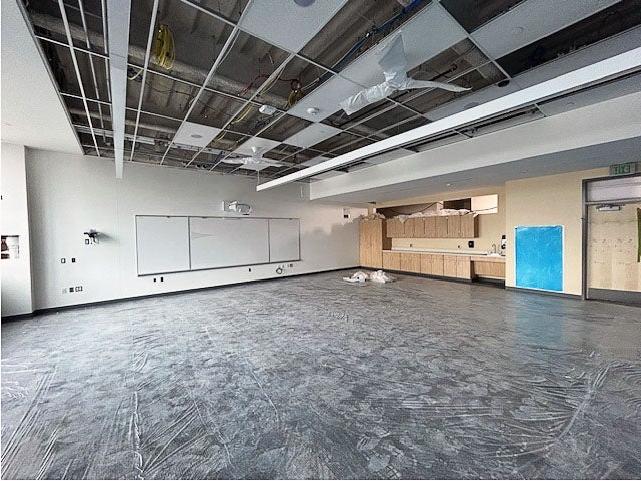 a large space with cabinetry and a white board and a ceiling grid