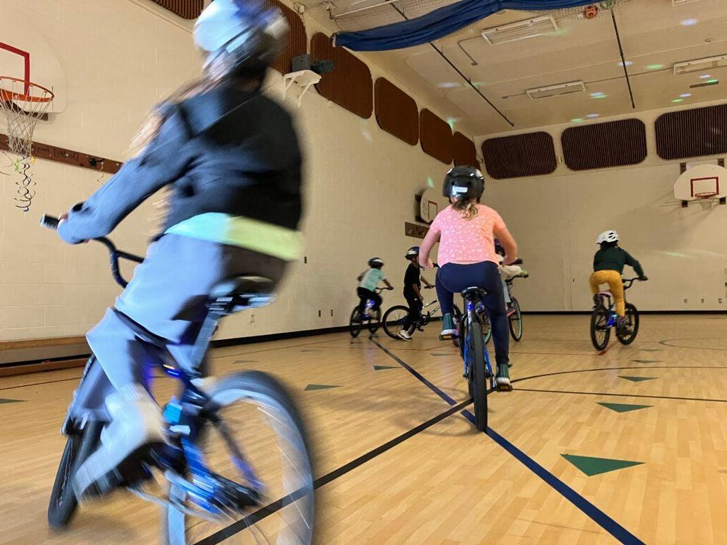 Students ride bikes in gym.