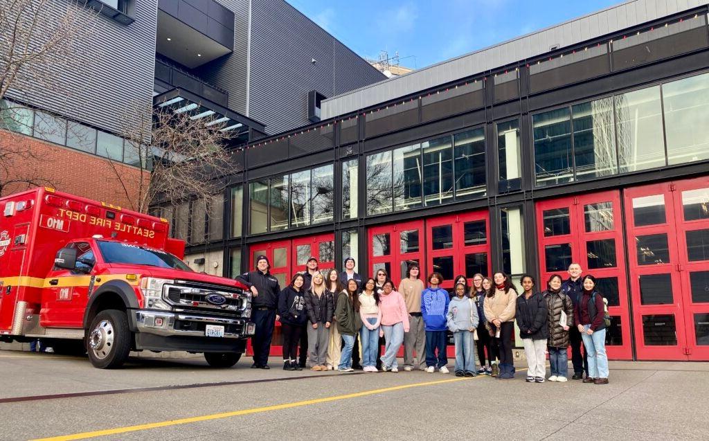 Students standing in front of fire station and fire truck during field trip