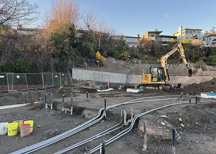 conduit running across dirt with pipes sticking up and construction equipment