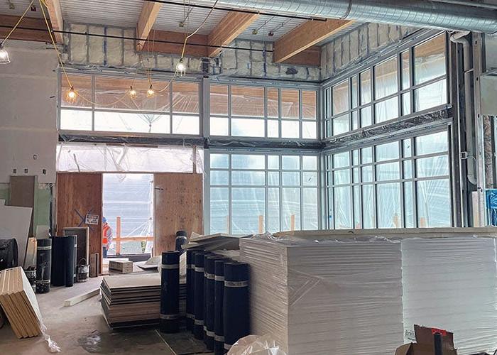 a large room with full height windows under construction with stacks of materials