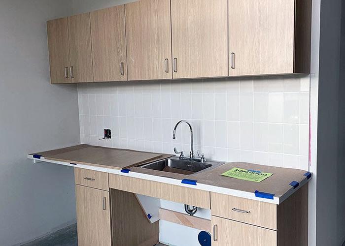 a sink and cabinets with a tile backsplash