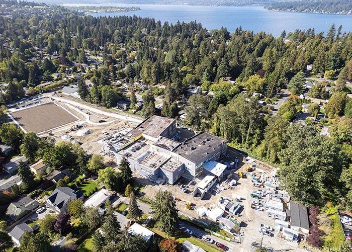 aerial of a building under construction with a square dirt field to the right