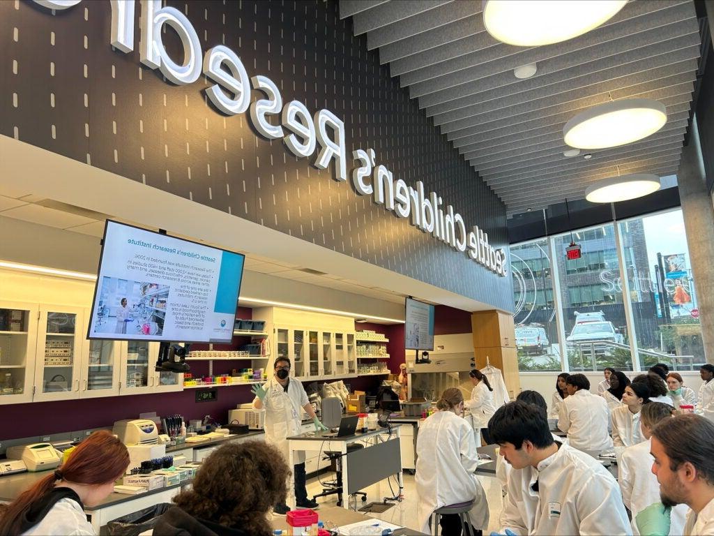 Students wearing white lab coats in health and medical research lab