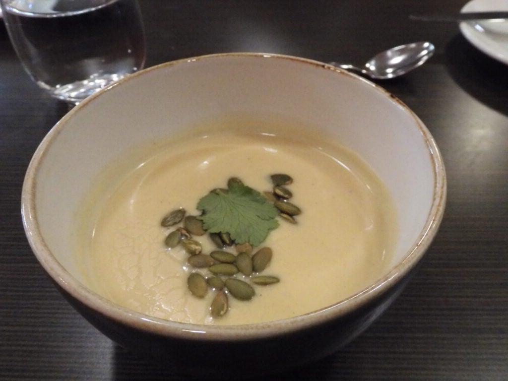 soup in white bowl with pumpkin seeds