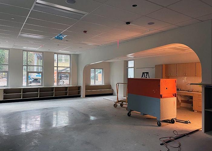 a large room with an arch divider, windows, and cabinetry