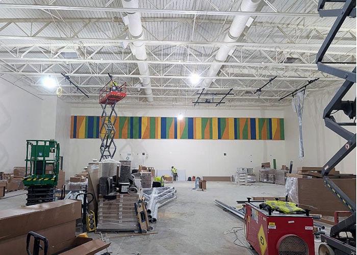 a gymnasium under construction wth a scissor lift and a colorful wall panel