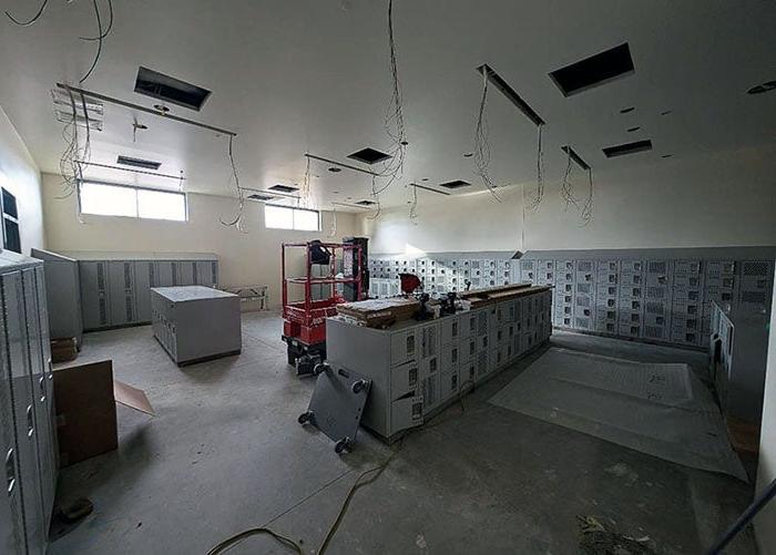 a room with wires for lights and banks of lockers being installed