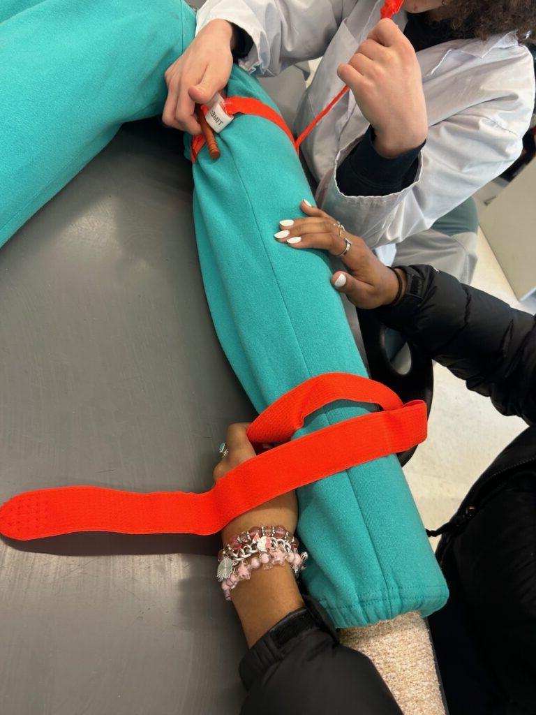 Students practicing tourniquet placement on a fake arm