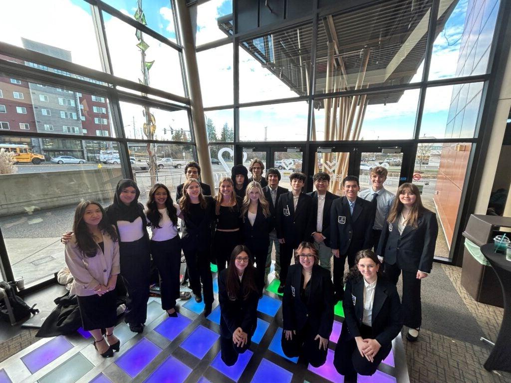 students posing in front of large window at competition