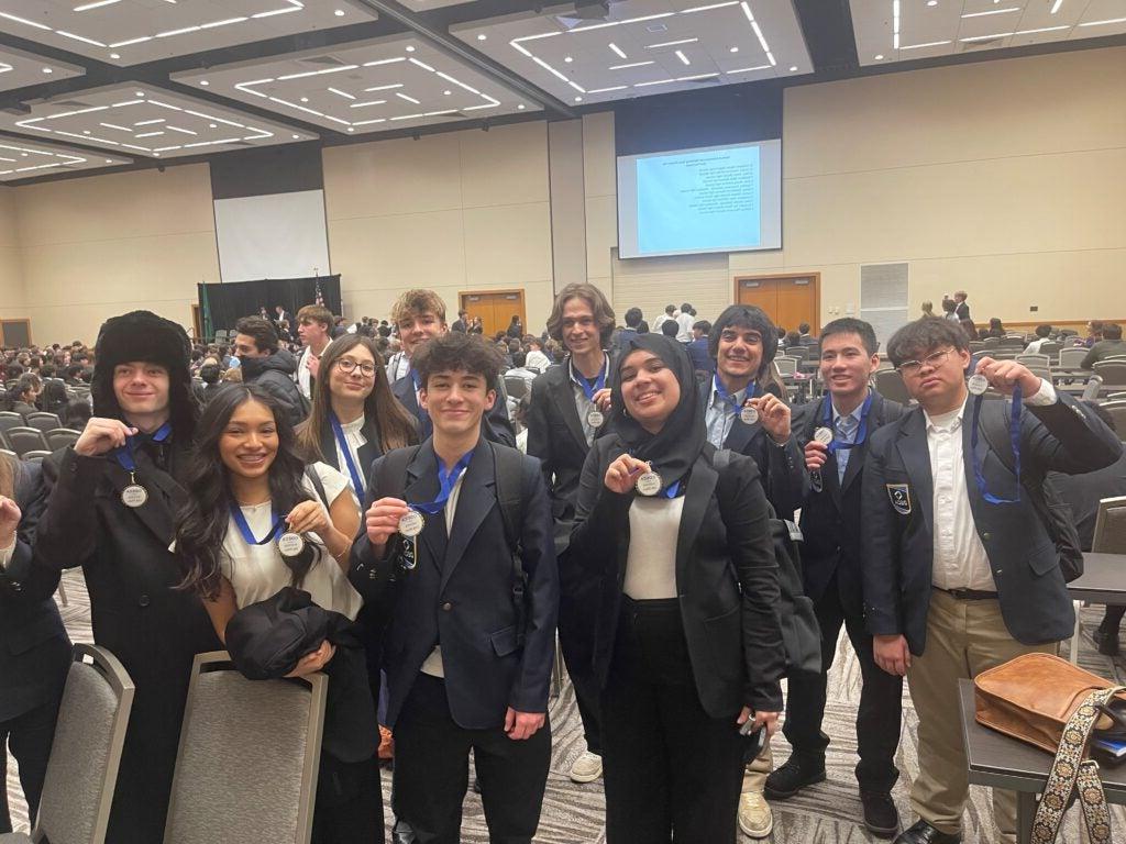 students in suits holding medals