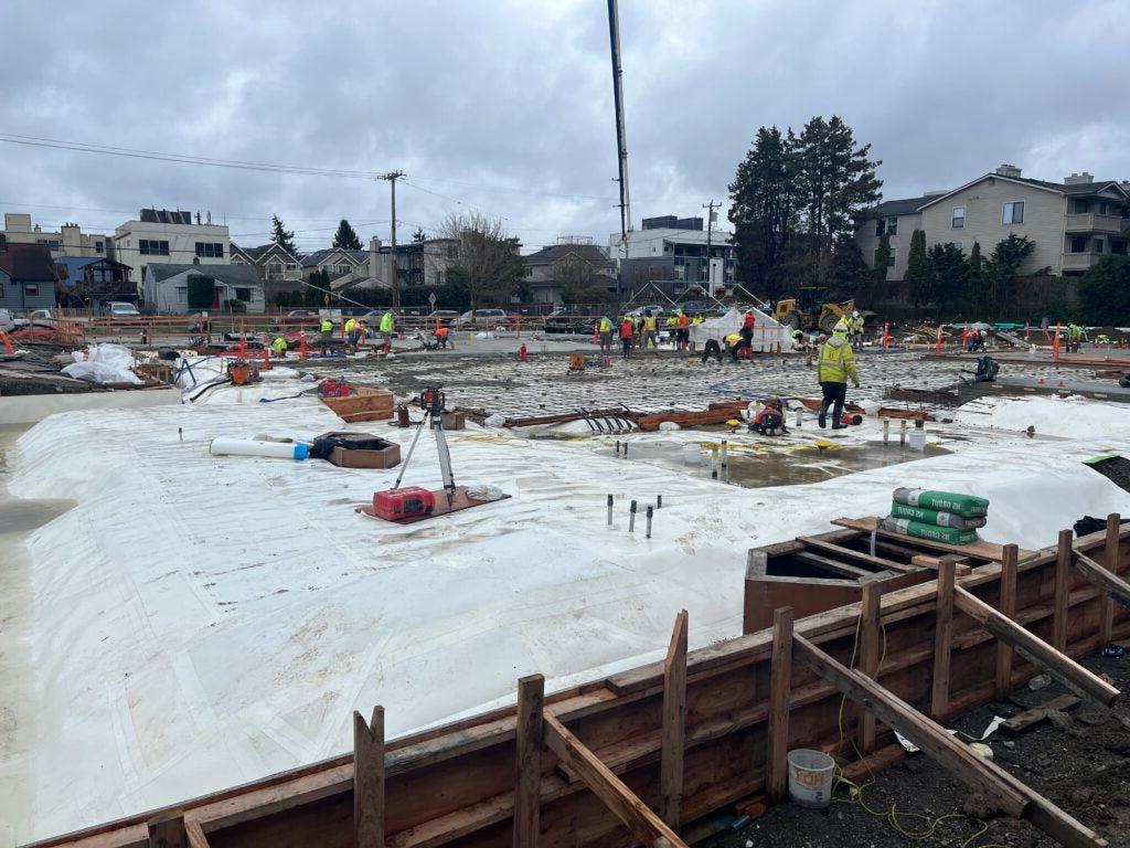 workers begin to spread concrete at a construction site